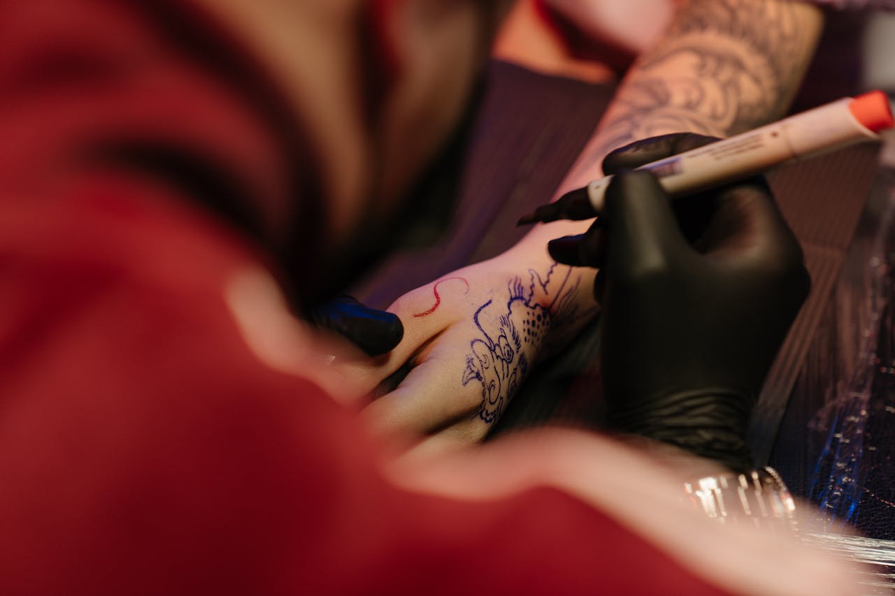 A tattoo artist drawing an intricate dragon design on a customer