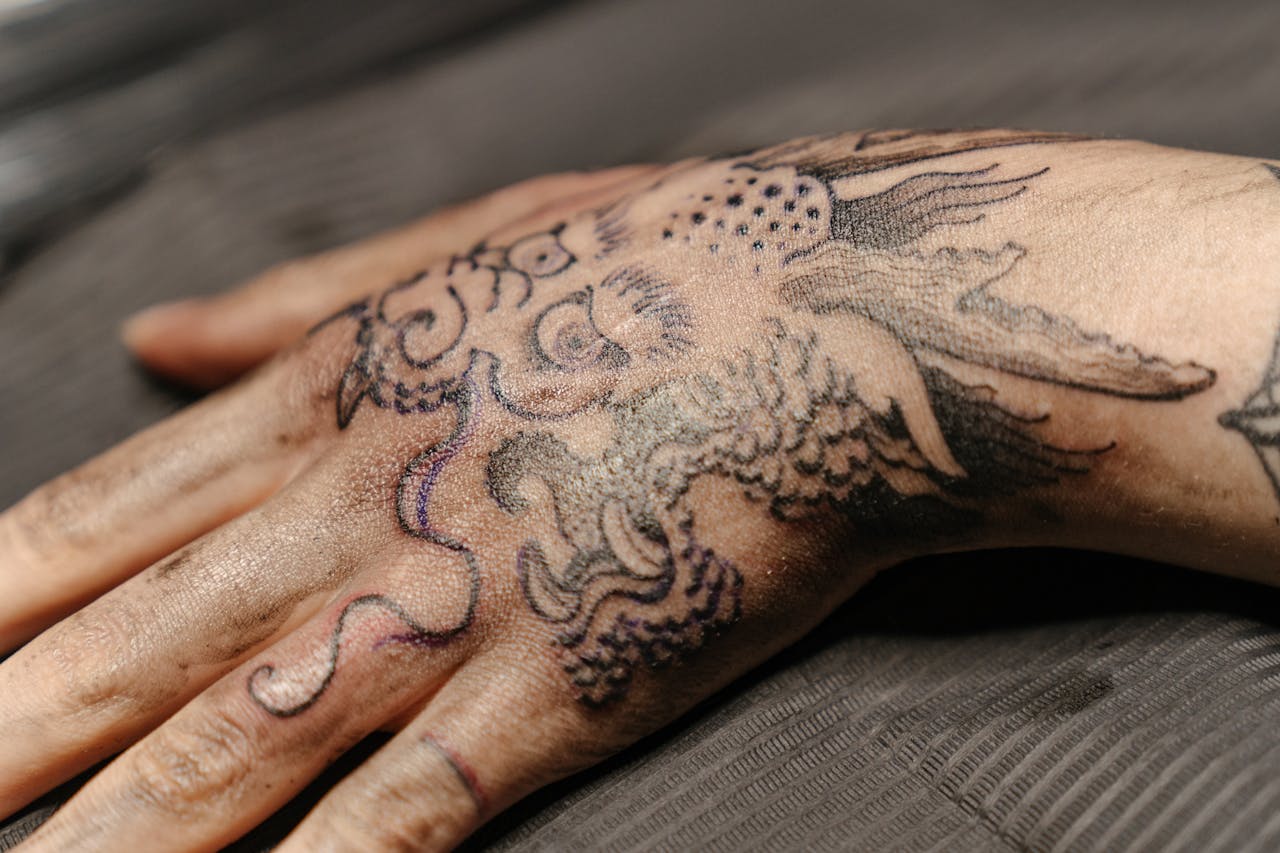 Close-up view of a detailed hand tattoo featuring a dragon design in a tattoo studio.