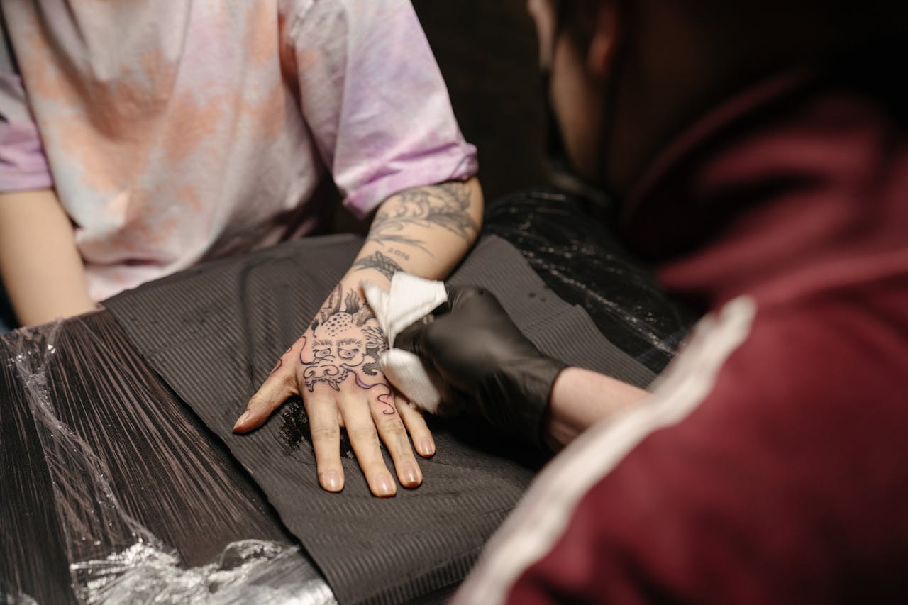 Close-up of a tattoo artist creating a detailed hand tattoo in a professional studio.